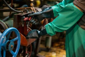 Butler Holding Company Industrial worker in protective gear handling a valve in a factory setting, ensuring safety and precision.
